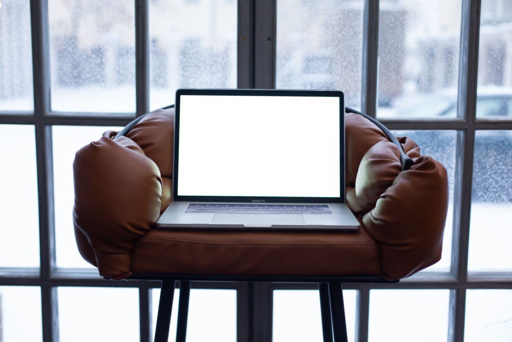 Laptop on a leather armchair in front of a frosted, snowy window